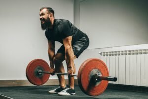 Muscular man in black deadlifting in gym