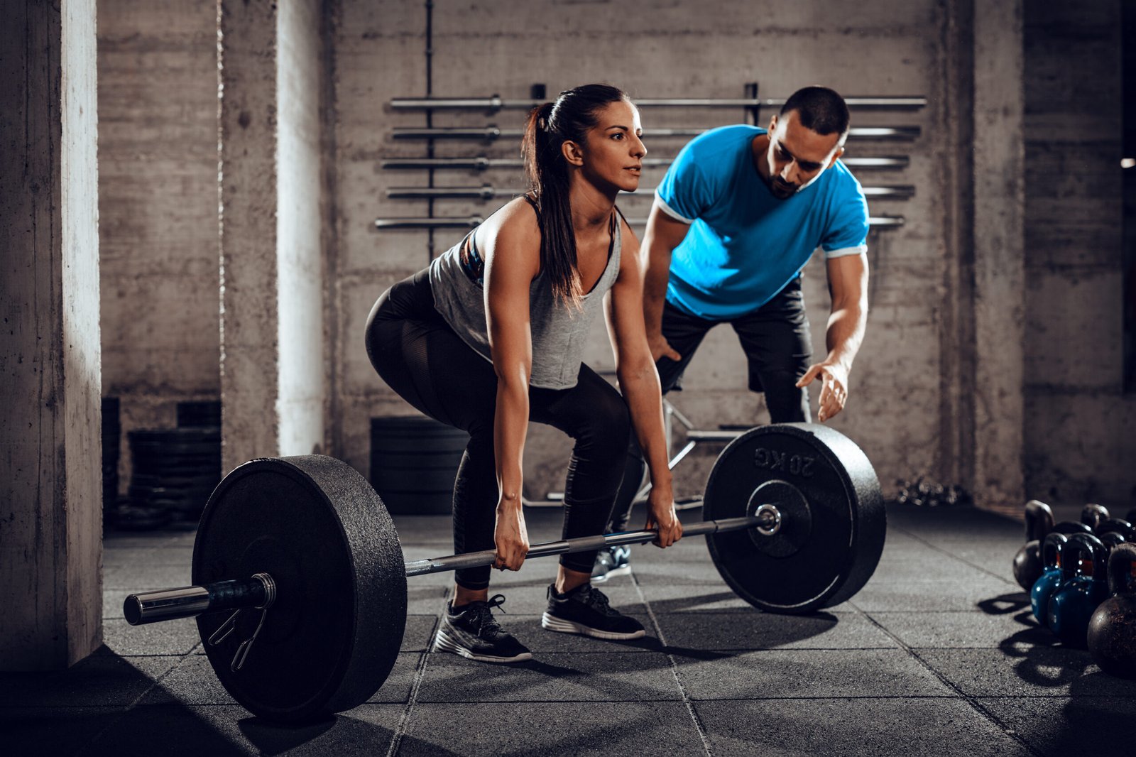 Young woman doing hard exercise at the gym with a personal trainer. book an intro at STRONGlab NYC